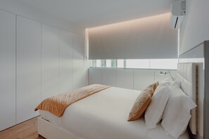 Un dormitorio moderno con cama, ventana y equipo de aire acondicionado.