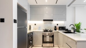 A modern kitchen with a built-in washer, oven, and microwave. - Easygo- Luxury 1bdr With View Bin Can (Dubai)