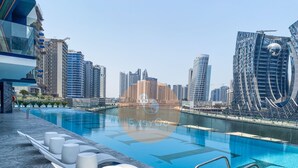A modern pool area with lounge chairs and a view of a city skyline. - Easygo- Luxury 1bdr With View Bin Can (Dubai)
