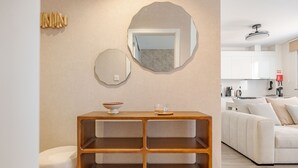 Un soggiorno moderno con un tavolino consolle in legno, un divano bianco e un angolo cottura sullo sfondo.