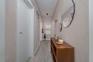 Ein Flur mit einer hölzernen Bank, einem Wandspiegel und einer kleinen Pflanze.