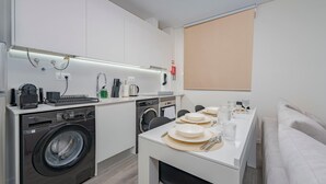 Una cucina moderna con lavatrice, macchina per caffè e zona pranzo con tavolo apparecchiato per due.