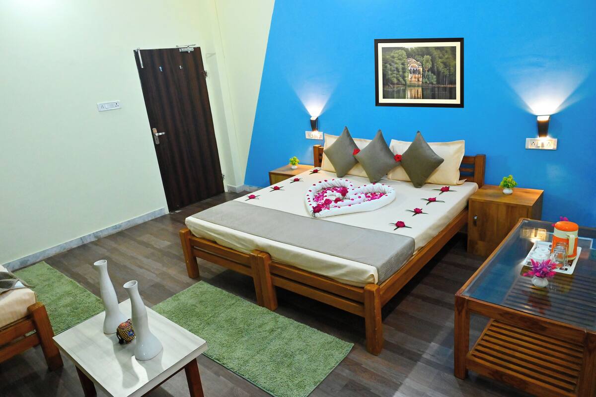 A bedroom with a bed, bedside tables, a nightstand, a green rug, and a framed picture on the wall.