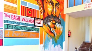 Un vestíbulo con un mural de colores, un sofá negro, una mesa de centro de madera y una escalera.