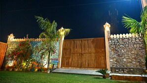 Una propiedad resguardada por un muro de piedra, un portón de madera y una entrada bien iluminada.