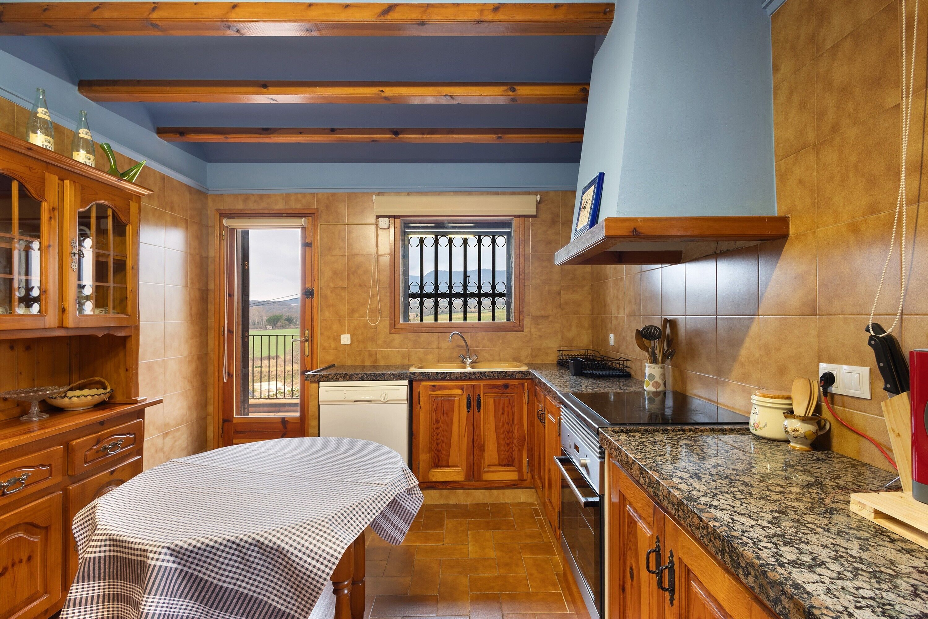 A kitchen with wooden cabinets, a granite countertop, and a window with a view.
