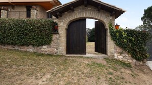 Un arc en pierre mène à une porte en bois sombre, qui est elle-même entourée d’un mur de pierre et de verdure.