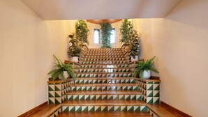 Un escalier orné de carreaux aux motifs géométriques, avec des rampes en bois et des plantes en pot.