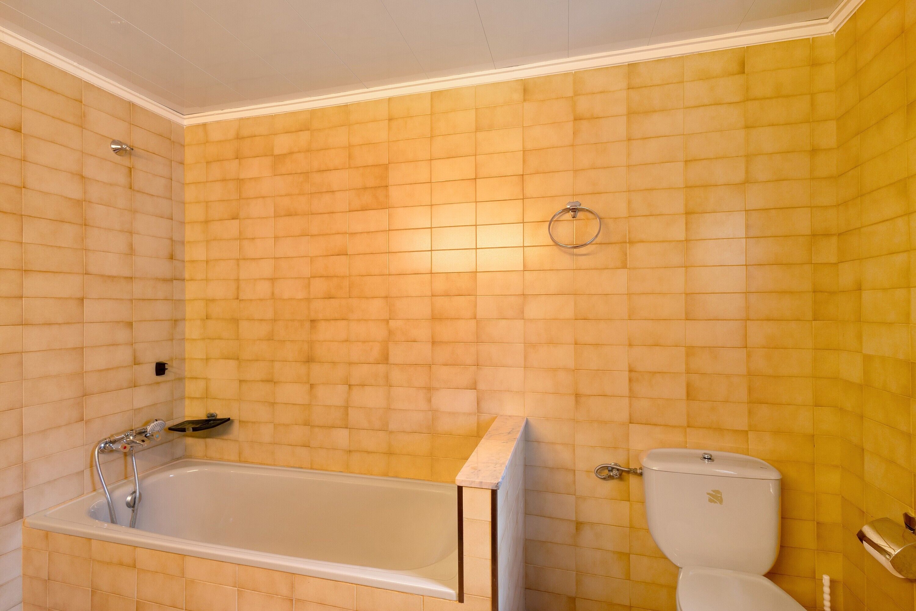 Een badkamer met een bad, toilet en een handdoekhouder aan de muur.