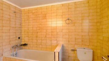 Een badkamer met een bad, toilet en een handdoekhouder aan de muur.