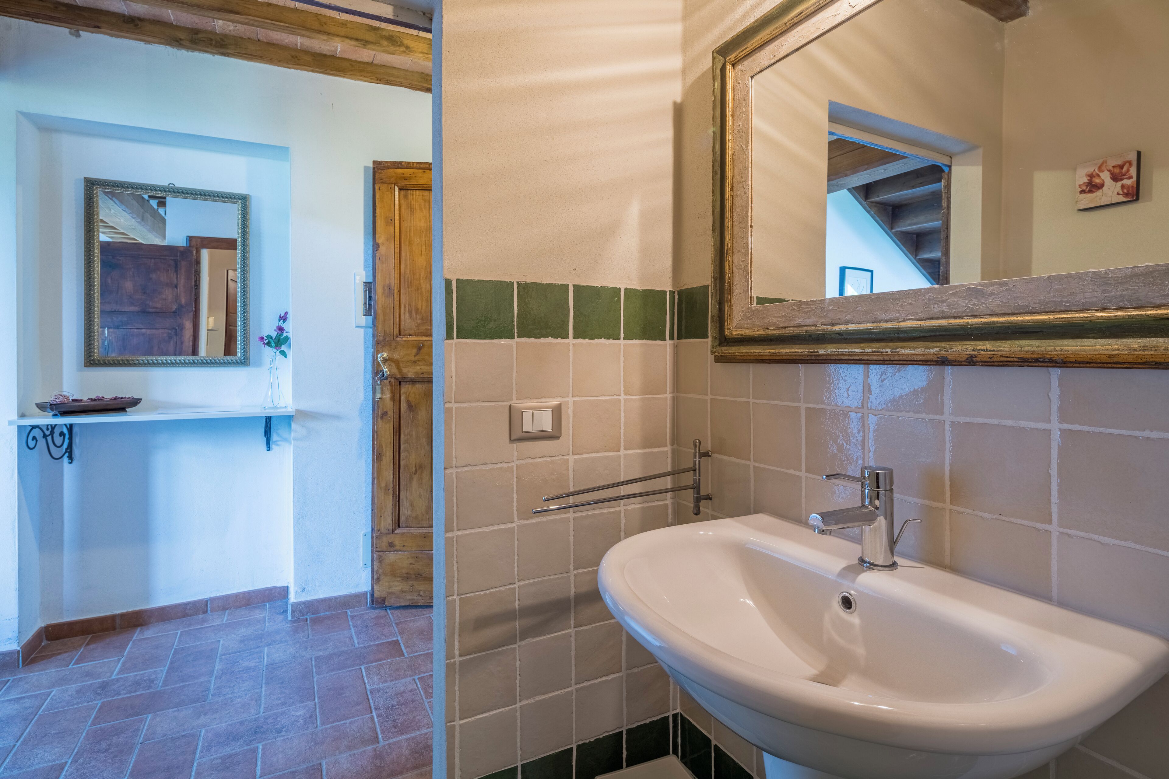 Un baño con lavamanos, espejo y paredes con azulejos.