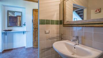 Un baño con lavamanos, espejo y paredes con azulejos.