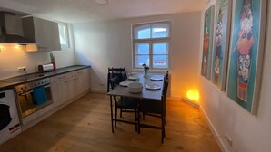 Et lille køkken med spisebord, stole og et vindue.