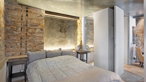 A bedroom with a large bed, a stone wall, a window, and a wardrobe. - Apartment 'La Cantina' with Sea View, Shared Garden and Wi-Fi (Imperia)