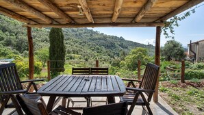 A wooden outdoor seating area with a table and chairs, overlooking a mountainous landscape. - Apartment 'La Cantina' with Sea View, Shared Garden and Wi-Fi (Imperia)