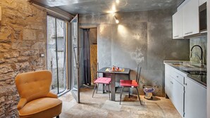 A modern kitchen with a dining area, stone walls, and a large window. - Apartment 'La Cantina' with Sea View, Shared Garden and Wi-Fi (Imperia)