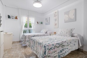 A bedroom with two beds, a window with curtains, a shelf with books, and a wall with a butterfly painting. - Apartment 'Exclusivo Con Vistas' with Private Terrace, Balcony and Wi-Fi (Conil de la Frontera)