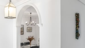 Un comedor con candelabro, paredes blancas y un elemento decorativo en la pared.