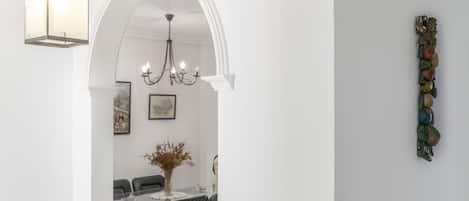 Ein Essbereich mit einer Chandelier, weißen Wänden und einer Wanddekoration.