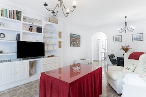 A living room with a TV, white furniture, a red table, and a white sofa. - Apartment 'Exclusivo Con Vistas' with Private Terrace, Balcony and Wi-Fi (Conil de la Frontera)
