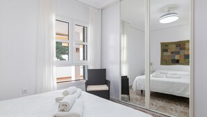Habitación de hotel con una cama grande, una silla, un espejo y un ventanal con cortinas.