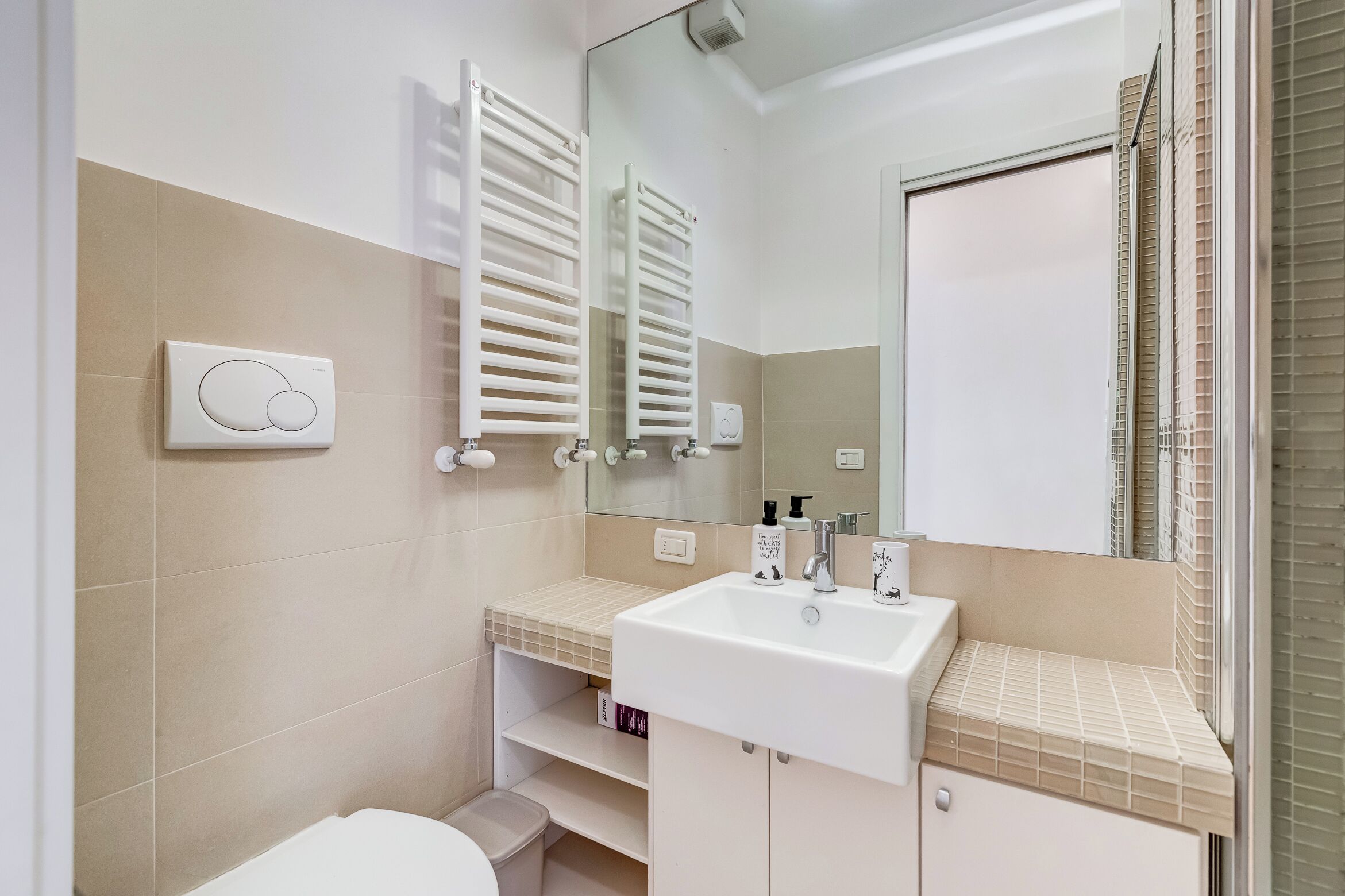 Une salle de bain avec un lavabo blanc, un miroir, des porte-serviettes et des toilettes.