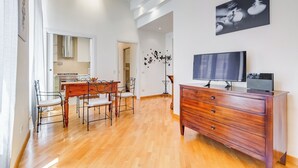 A modern living room with a wooden dining table, chairs, a TV, and a dresser. - Crescenzio St Peter House  (Rome)