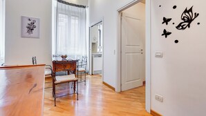 A room with a wooden floor, a dining table with chairs, a bed, and a door leading to another room. - Crescenzio St Peter House  (Rome)
