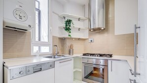 A modern kitchen with white cabinetry, a built-in oven, a gas stove, and a window providing natural light. - Crescenzio St Peter House  (Rome)