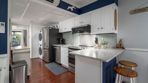 Una cocina moderna con armarios blancos, electrodomésticos de acero inoxidable y una pared azul de acento.