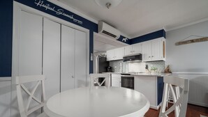 Una cocina con armarios blancos, una mesa de comedor blanca y una pared azul de acento.
