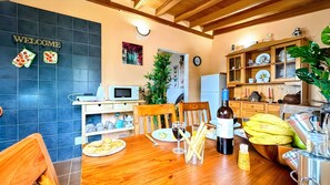 Une cuisine équipée d’une table en bois, d’un four à micro-ondes, d’un réfrigérateur et d’un coin repas avec des chaises.