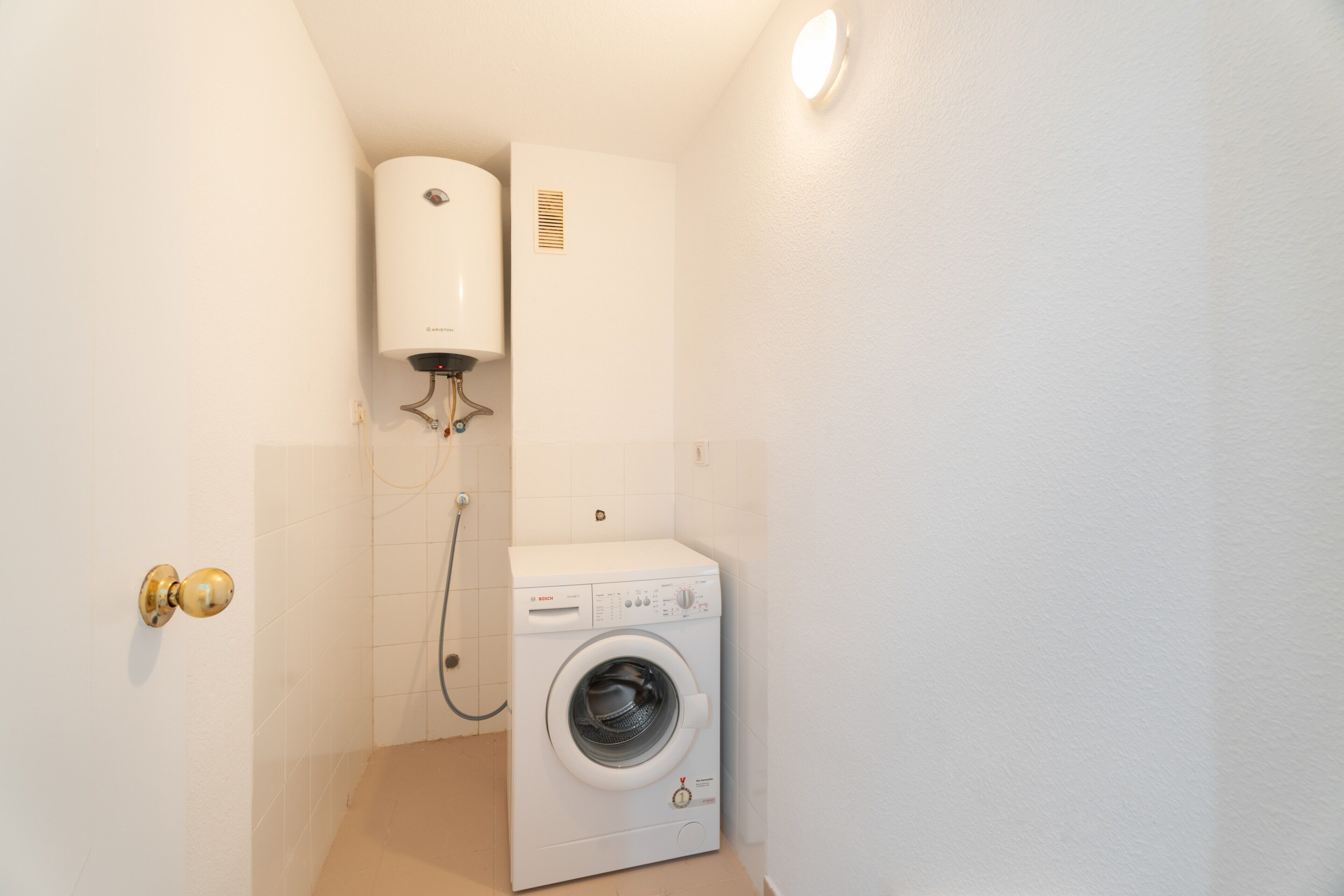 Une petite buanderie équipée d’un lave-linge et d’un sèche-linge fixé au mur.