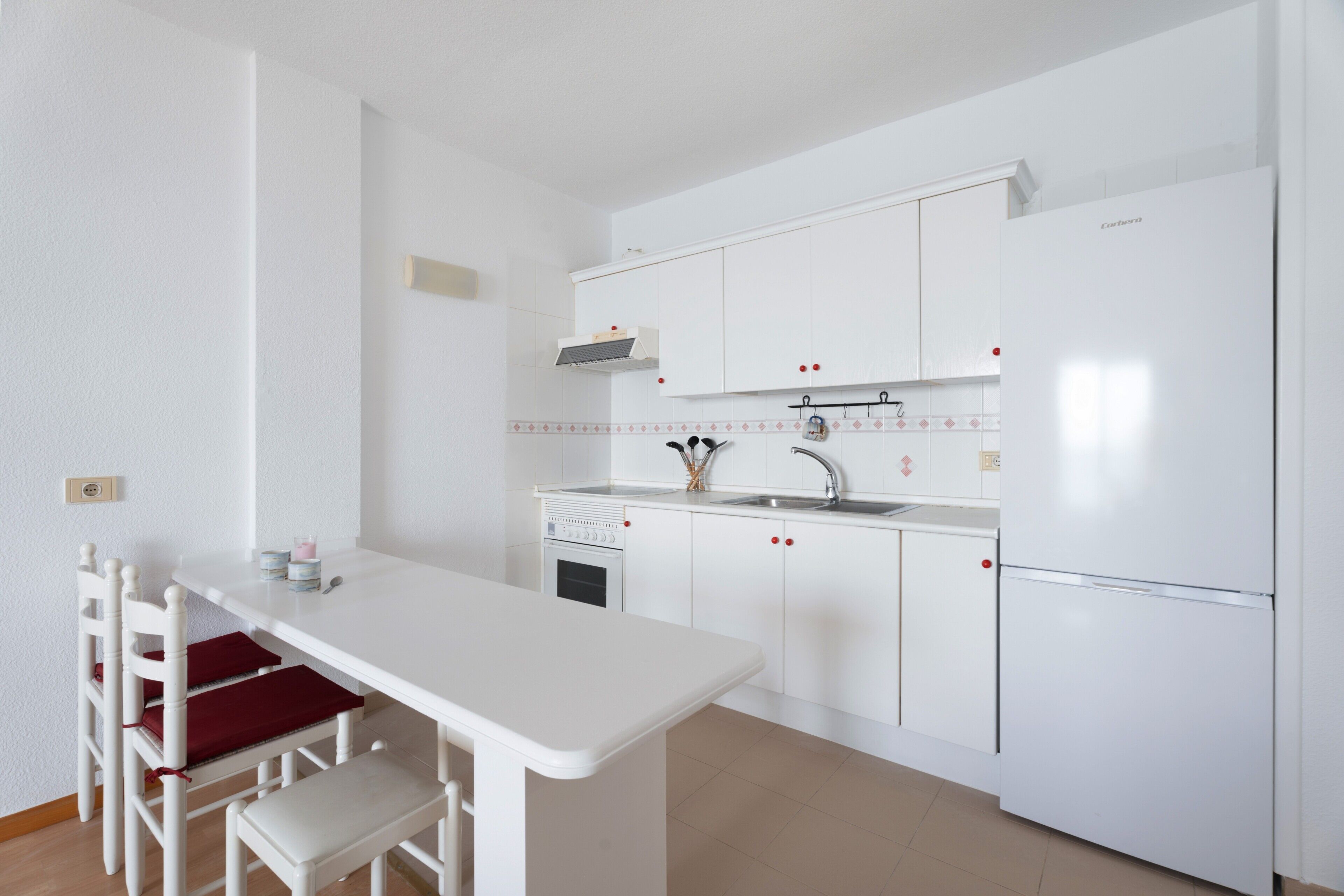 Una cocina compacta con muebles blancos, horno empotrado y una pequeña encimera.