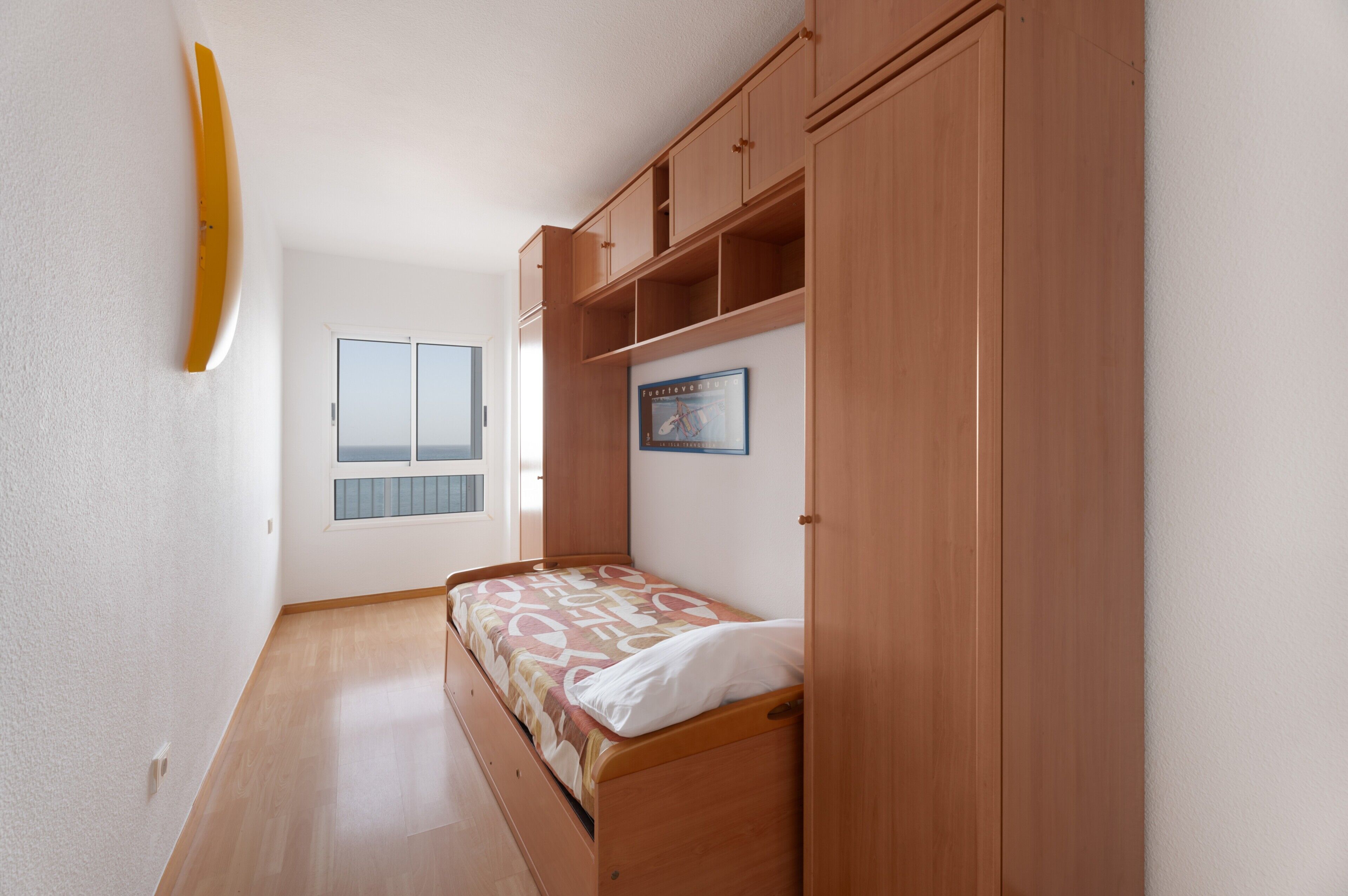 Una camera da letto con un letto singolo, un armadio in legno e una finestra con persiane.