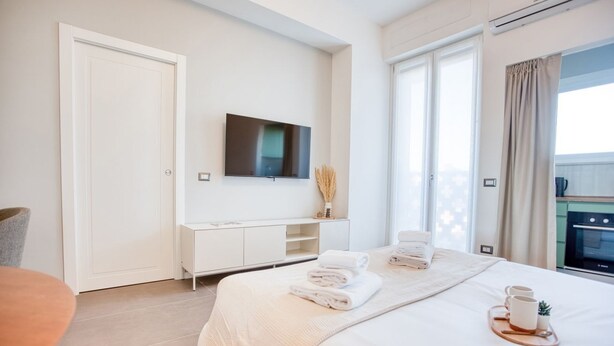 Ein Hotelzimmer mit Bett, Fernseher, Schreibtisch und einem Fenster mit Vorhängen.