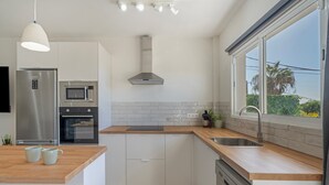 Eine moderne Küche mit einem Edelstahl-Kühlschrank, einer Mikrowelle, einem Backofen und einer Holzarbeitsplatte.