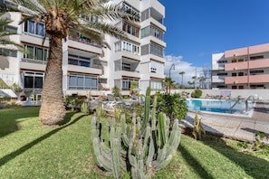 Un immeuble à plusieurs étages doté de balcons, d’une piscine et d’un jardin de cactus.