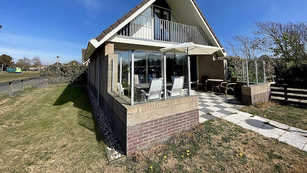 A modern house with a glass conservatory, a balcony, and a checkered pathway leading to the entrance. - 3 bedroom accommodation in Callantsoog (Callantsoog)