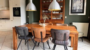 A dining area with a wooden table and chairs, a kitchen with white cabinets, and a radiator. - 3 bedroom accommodation in Callantsoog (Callantsoog)