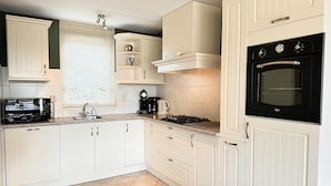 A modern kitchen with white cabinetry, a black oven, and a tiled backsplash. - 3 bedroom accommodation in Callantsoog (Callantsoog)