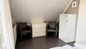 A small, neatly arranged room with a bed, two chairs, a dresser, and a refrigerator. - 3 bedroom accommodation in Callantsoog (Callantsoog)