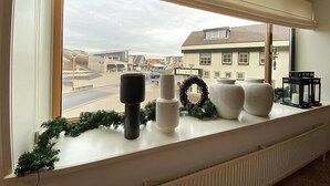 Ein Fensterbrett mit Dekoration, Blick auf eine Straße und Gebäude im Hintergrund.