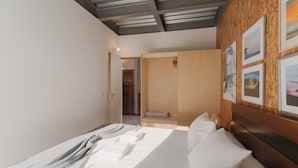 Moderni hotellihuone, jossa on sänky, puinen pääty ja taideteoksia seinillä.