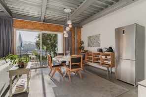 Una cocina moderna con un refrigerador de acero inoxidable, sillas de madera, una mesa de comedor y un ventanal con vistas.