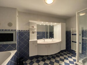 A bathroom with a white sink, two mirrors, a white cabinet, and a checkered floor.