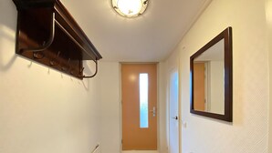 A hallway with a coat rack, a door with a window, a mirror, and a bench. - Callantsoger Staete A107 (Callantsoog)