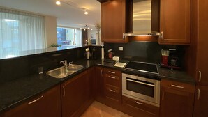 A modern kitchen with wooden cabinets, stainless steel appliances, and a black countertop. - Callantsoger Staete A107 (Callantsoog)