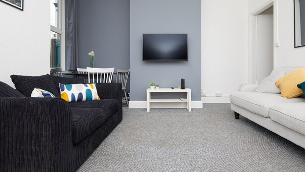 Una sala de estar moderna con un sofá gris, un sofá blanco y un televisor de pantalla plana montado en la pared.