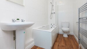 Un baño con lavamanos blanco, bañera, inodoro y ducha.